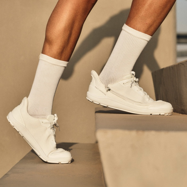 Someone walking up outdoor steps in white Arc trainers.