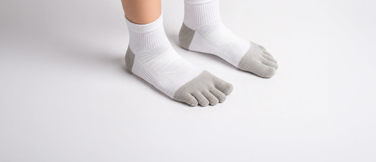 A person wearing a pair of quarter cut, white All-Day Toe Socks