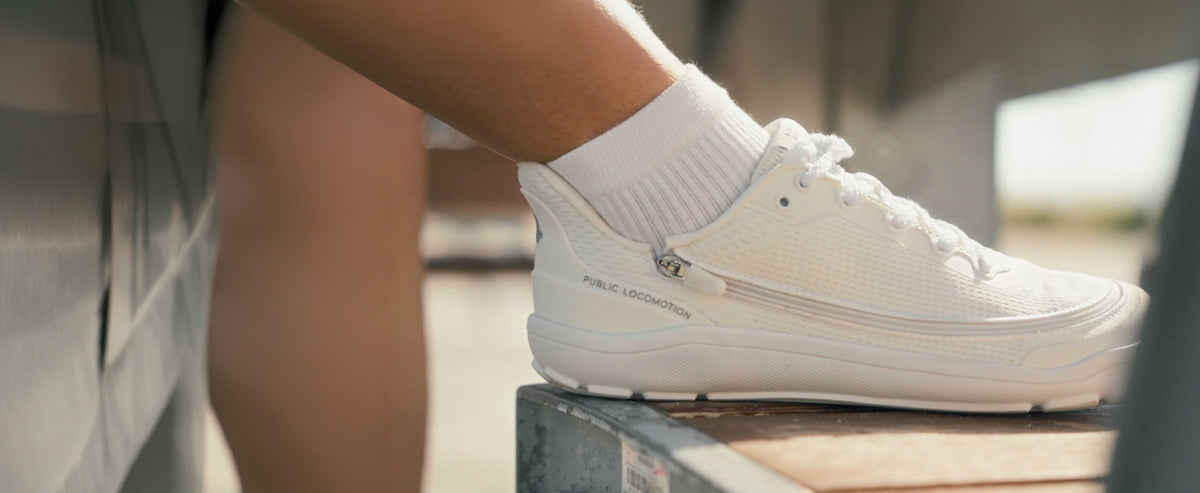 Side view of woman wearing white Arc trainers.