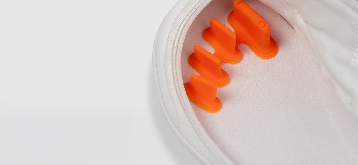 Close-up of an orange FeetFormer inside an unzipped white Arc trainer.